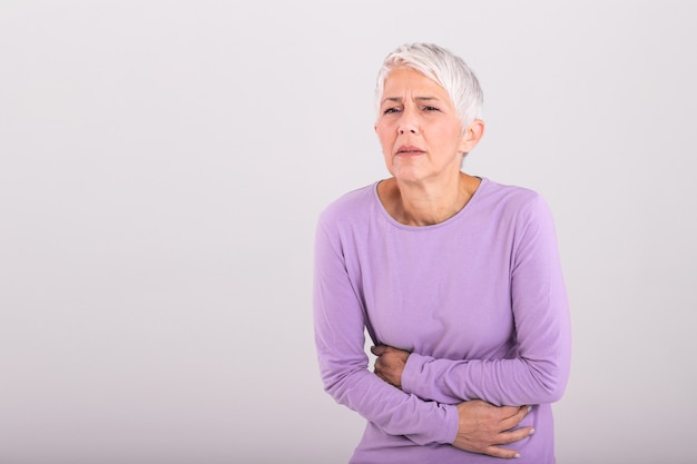 Femme mature malsaine tenant le ventre, sensation d'inconfort, concept de problème de santé, femme âgée malheureuse assise sur le lit, souffrant de maux d'estomac