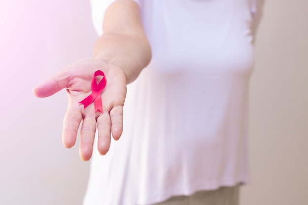 Femme mature avec un ruban rose isolé sur blanc. Image du Mois de la sensibilisation au cancer du sein.