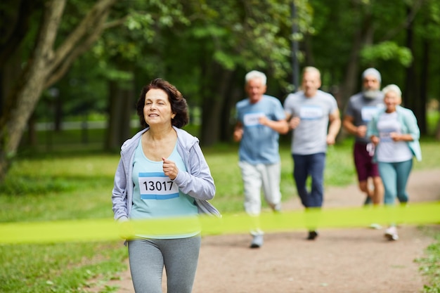 Femme mature sportive active aux cheveux bruns prenant part à la course de marathon en le terminant en premier, copiez l'espace