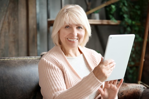 Femme mature avec tablette à la maison