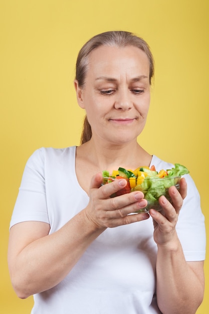 Femme mature tenant une assiette de salade de légumes