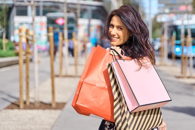 une femme mature tenant des sacs d'achat sur son épaule