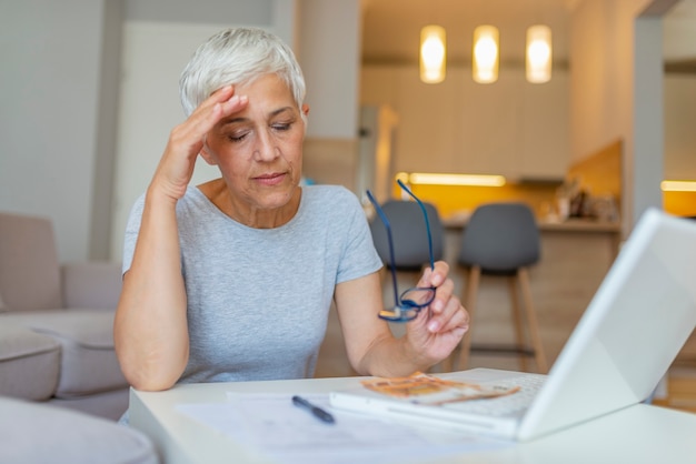 Femme mature travaillant avec des documents à table à la maison.