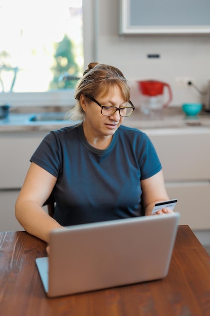 Femme mature utilisant une carte de crédit pour effectuer un paiement en ligne à la maison