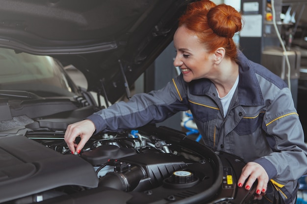 Femme mécanicien travaillant à la station service de voiture