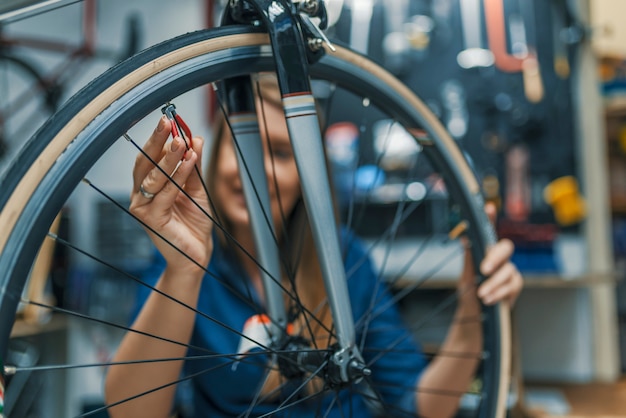 Femme de mécanicien de vélo élégant faisant son travail professionnel dans l&#39;atelier.