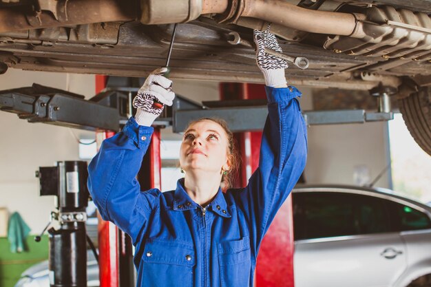 Une femme mécanicienne vérifie la suspension d'une voiture dans un garage