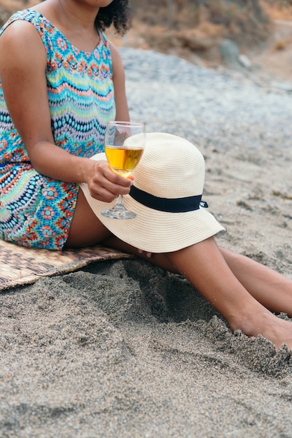 Femme méconnaissable avec chapeau et verre à vin