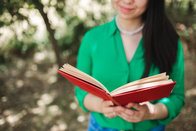 Femme méconnaissable avec un chemisier vert lisant un livre dans la forêt Journée mondiale du livre