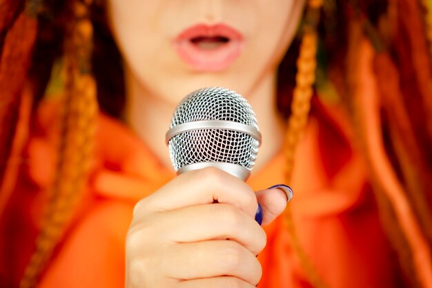 Femme méconnaissable avec des dreadlocks chantant dans le microphone Plein cadre Partie du corps de la femme avec micro Mise au point sélective Gros plan