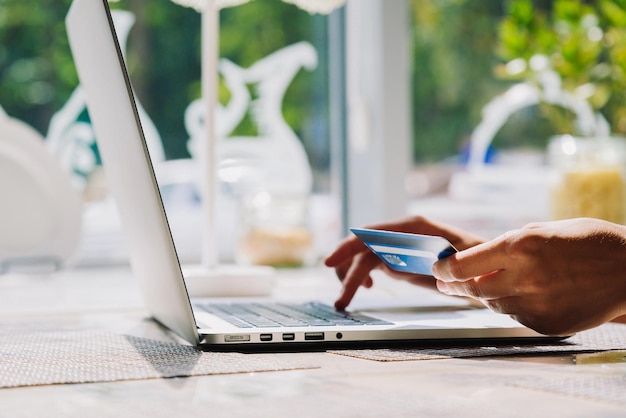 Photo femme méconnaissable faisant des achats en ligne avec carte de crédit à l'aide d'un ordinateur portable au café