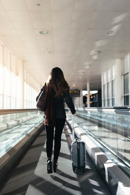 Femme méconnaissable marchant avec une valise à l'aéroport. Concept d'entreprise.