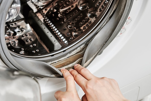 Une femme méconnaissable nettoie la machine à laver