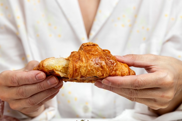 Femme méconnaissable prenant son petit déjeuner en pyjama à la maison