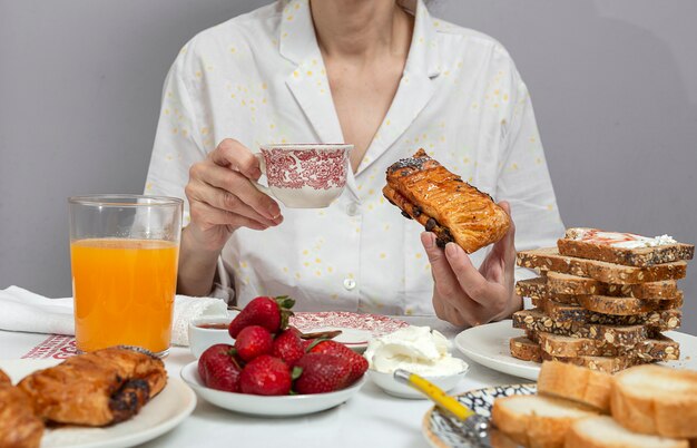 Femme méconnaissable prenant son petit déjeuner en pyjama à la maison