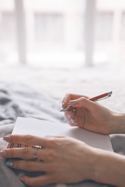 Une femme méconnaissable prend des notes dans un livre d'écriture.