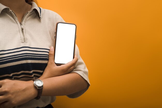 Femme méconnaissable tenant un smartphone sur fond jaune Écran vide pour la conception de votre application