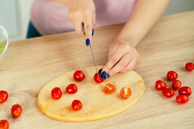 Une femme méconnaissable tranche des tomates cerises pour une salade debout dans une cuisine moderne Vitamines nutrition diététique et sportive Nourriture végétarienne