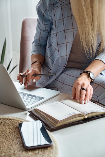 Femme méconnaissable utilisant un ordinateur portable assis sur une chaise au bureau à domicile