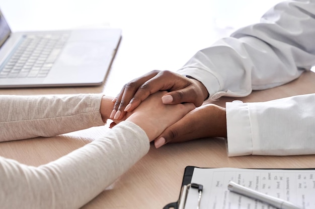 Femme médecin africaine tenant la main soutenant un patient caucasien vue rapprochée