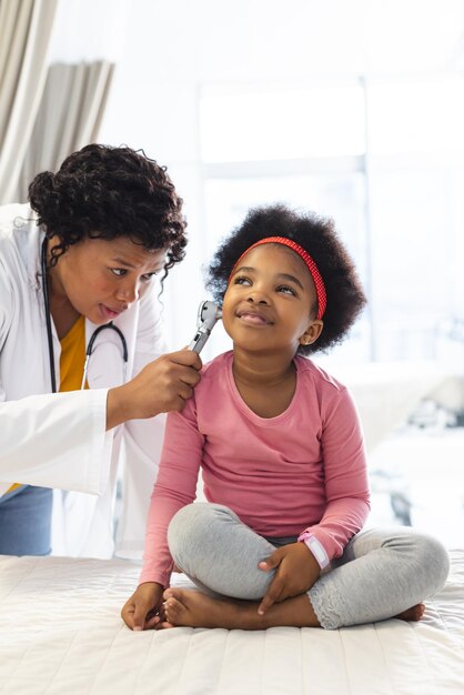 Photo une femme médecin afro-américaine examine une patiente en utilisant l'otoscopie à l'hôpital