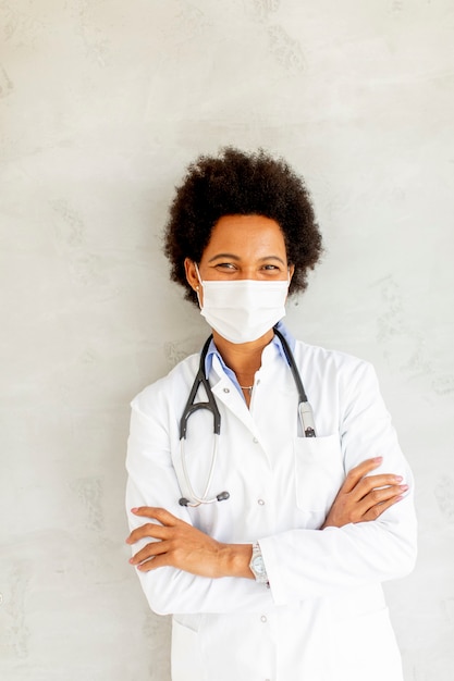 Une femme médecin afro-américaine porte un uniforme blanc et un masque facial protecteur à l'hôpital