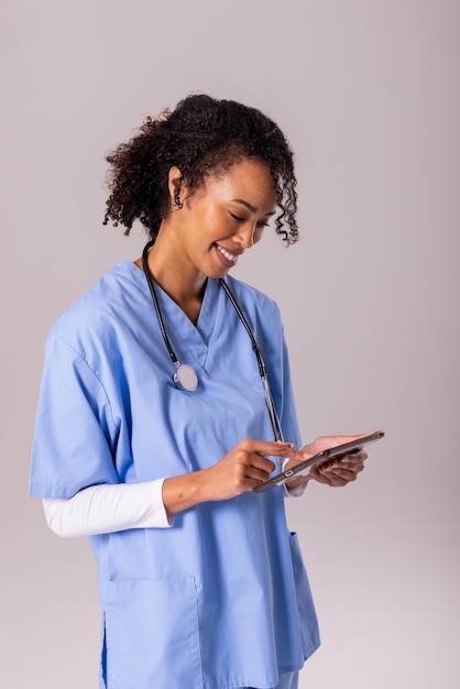 Photo femme médecin afro-américaine souriante d'âge moyen utilisant une table numérique sur fond blanc. technologie sans fil, stéthoscope, espace de copie, médecin, soins de santé, hôpital, profession médicale.