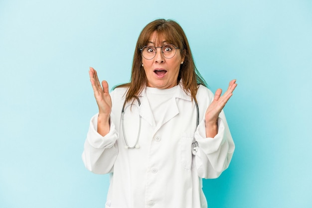 Femme médecin d'âge moyen isolée sur fond rose surprise et choquée.