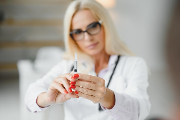 Femme médecin d'âge moyen tenant une seringue à la clinique