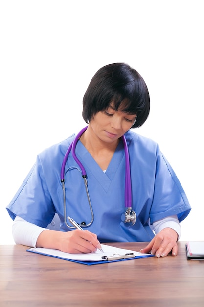 Femme médecin asiatique assise à table et écrivant avec un stylo à bille isolé