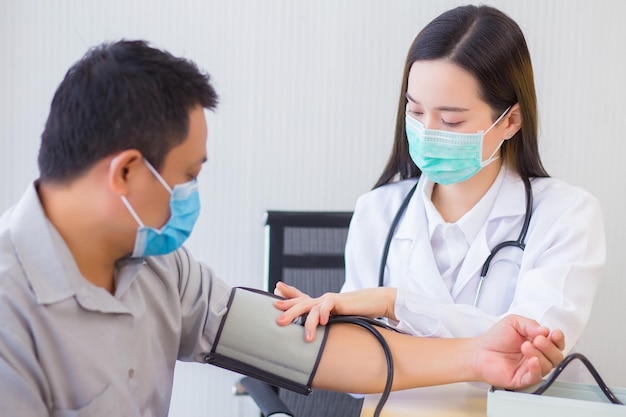 Une femme médecin asiatique professionnelle utilise un tensiomètre avec un homme patient pour vérifier sa santé