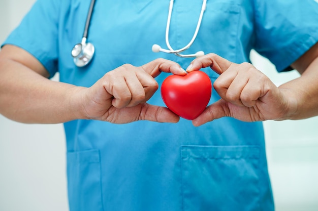 Femme médecin asiatique tenant un coeur rouge pour la santé à l'hôpital