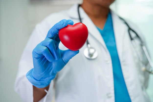 Femme médecin asiatique tenant un coeur rouge pour la santé à l'hôpital