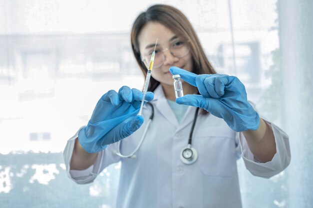 Femme médecin asiatique tenant le flacon de vaccin et la seringue.