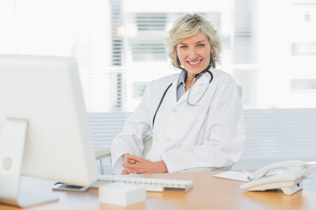 Femme médecin assis avec un ordinateur au cabinet médical