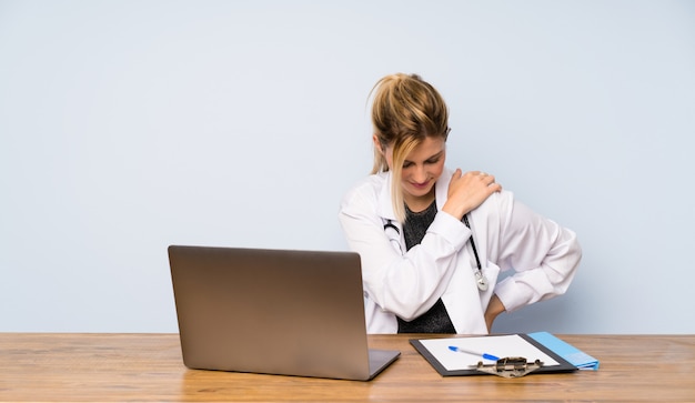 Femme médecin blonde souffrant de douleurs à l&#39;épaule pour avoir fait un effort