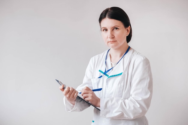 Femme médecin en blouse blanche fait une entrée dans le dossier sur fond blanc