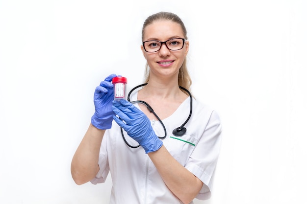 Femme médecin en blouse blanche et gants détient un récipient pour recueillir l'urine sur fond blanc