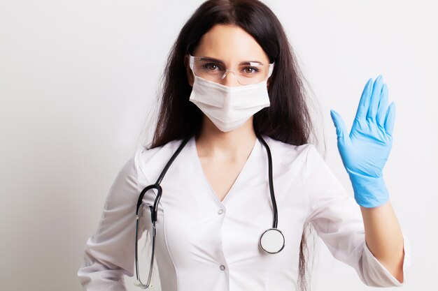 Femme médecin en blouse blanche montre le geste d'arrêt des mains