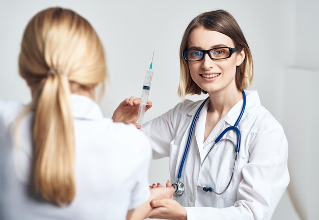 Une femme médecin en blouse médicale fait une injection à un patient