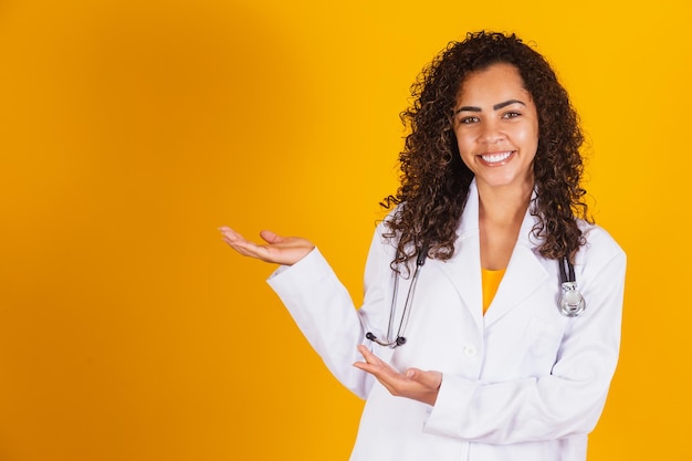 Femme médecin brésilienne souriante en blouse blanche pointant vers le côté