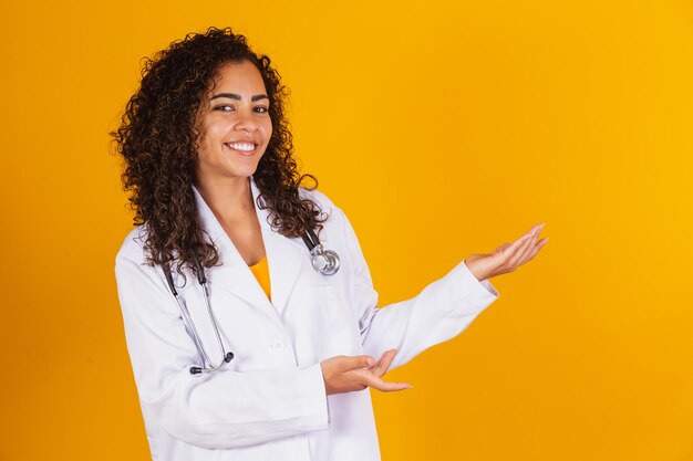 Femme médecin brésilienne souriante en blouse blanche pointant vers le côté