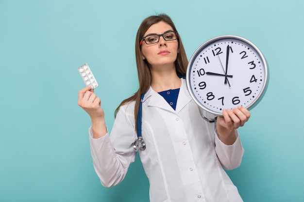 Femme médecin brune à lunettes avec horloge