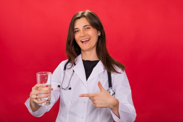 femme médecin brune pointant vers un verre d'eau