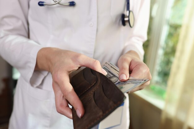 Une femme médecin cache de l'argent dans son portefeuille à l'hôpital