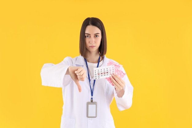 Femme médecin avec calendrier périodique et tampons sur fond jaune