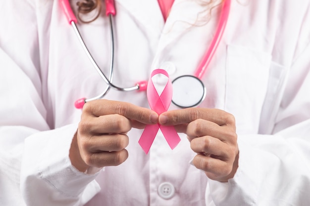 Femme médecin caucasienne avec stéthoscope rose tenant le ruban rose du cancer du sein.