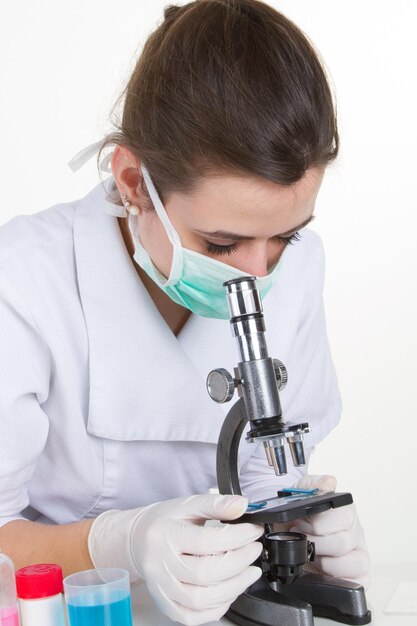 Femme médecin ou chercheuse scientifique en masque à l'aide d'un microscope dans un laboratoire