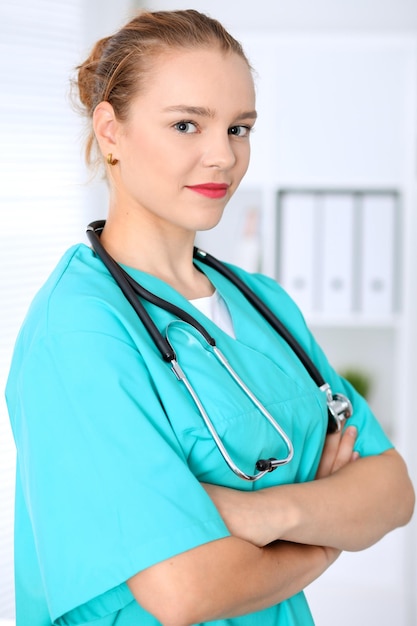 Femme médecin chirurgien est debout avec les bras croisés et souriant à l'hôpital. Médecin prêt à examiner le patient