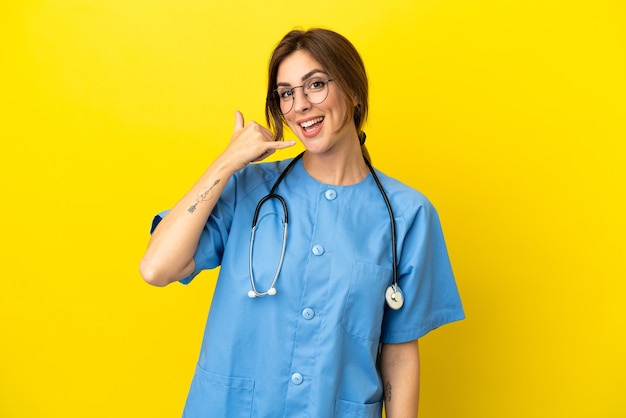 Femme médecin chirurgien isolée sur fond jaune faisant un geste de téléphone. Rappelle-moi signe